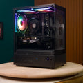 Destello Luz black gaming PC front-left view, tempered glass panel displaying RGB-lit components on wooden turntable