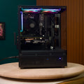 Destello Luz black gaming PC back three-quarter angle showing non-glass side panel and rear I/O with RGB strip along top